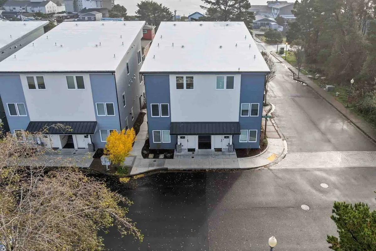 A vibrant exterior shot capturing modern townhouses with a yellow-leafed tree, paved sidewalk, and a classic lamp post. The scene is alive with the suggestion of walkability and community, set in an inviting neighborhood atmosphere perfect for enjoying local culinary outings.