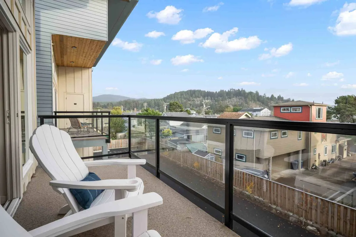 This image captures an exterior balcony featuring a single Adirondack chair next to the railing, overlooking a distant mountain view. The scene conveys solitude, relaxation, and the opportunity to soak in natural beauty, whether at sunrise or under the stars.