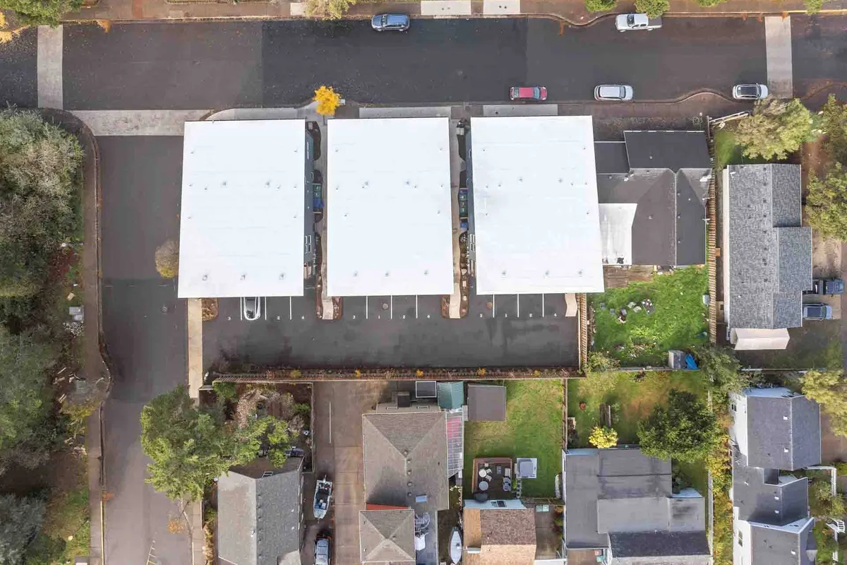 An exterior view of a quiet neighborhood with rows of white rooftops, well-kept green lawns, and parked cars. The calm setting hints at a family-friendly atmosphere, perfect for neighborhood walks, backyard gatherings, and relaxing after a day of adventure.
