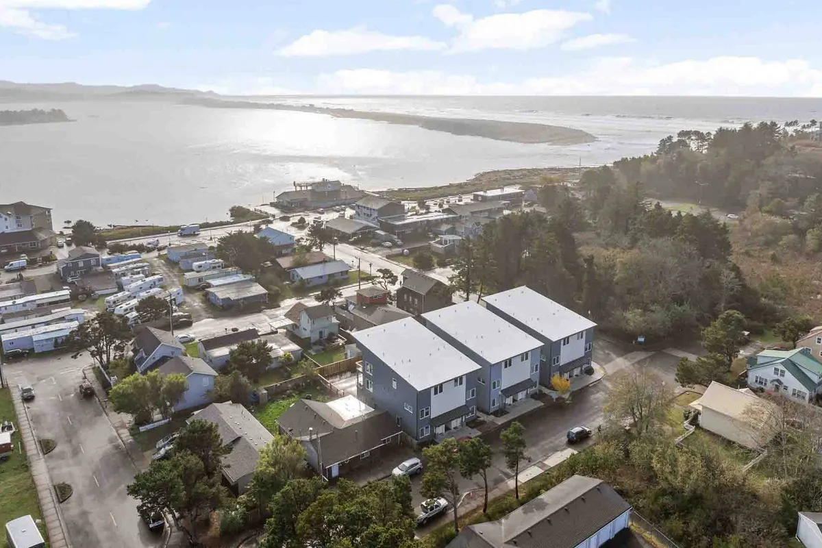 This image captures a serene waterfront view with houses nestled along the shoreline, visible roadways, and stretches of green spaces. The scene suggests opportunities for outdoor activities like boating, fishing, walking, and nature exploration. The overall mood is peaceful, evoking the allure of a scenic getaway close to water-based attractions.