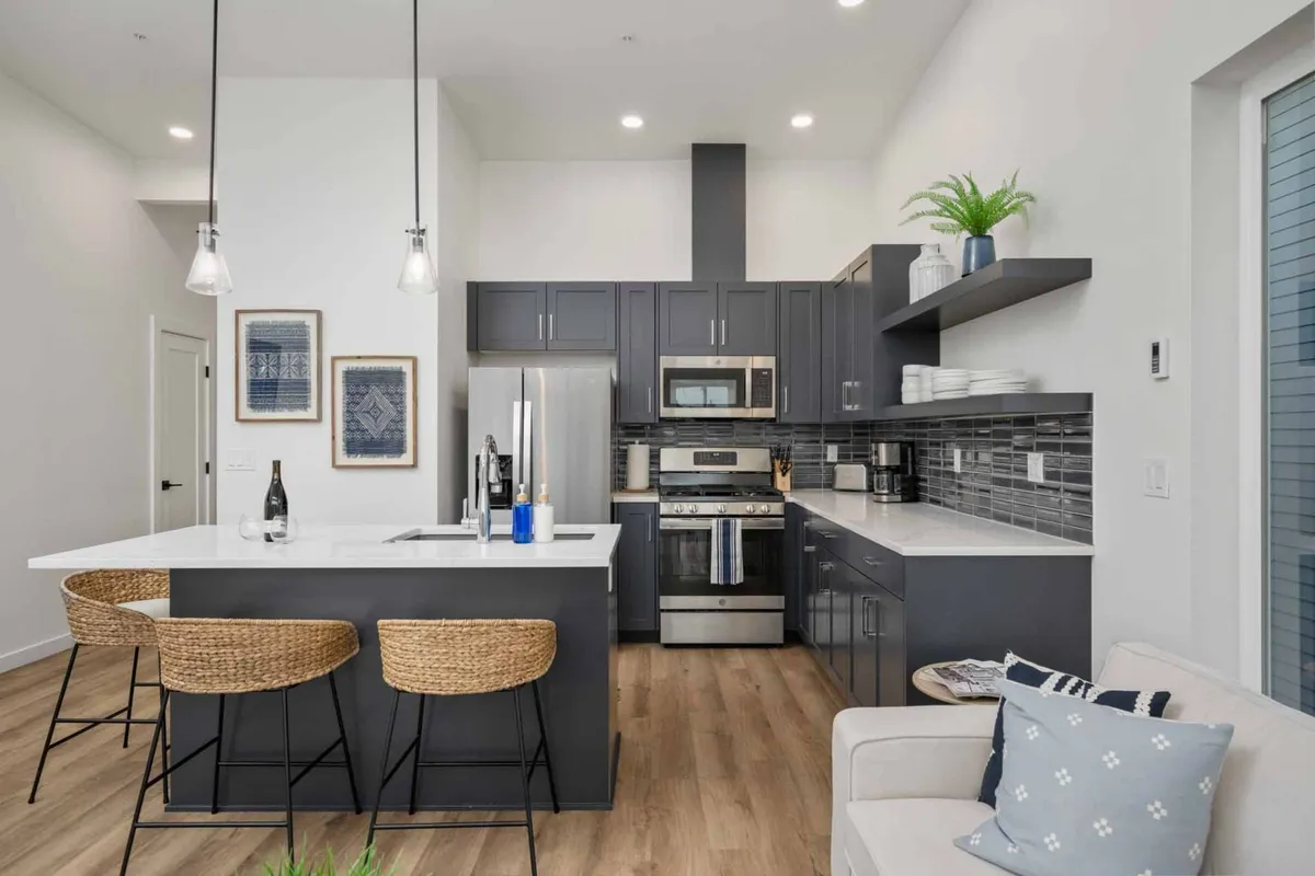 A contemporary kitchen with a prominent island, sleek stainless steel appliances, and comfortable bar stools. The space is accented by decorative wall art, blending style with functionality and highlighting the kitchen’s role as a social and culinary hub.